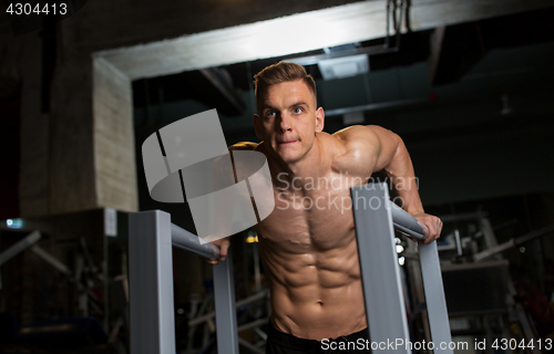 Image of man doing triceps dip on parallel bars in gym