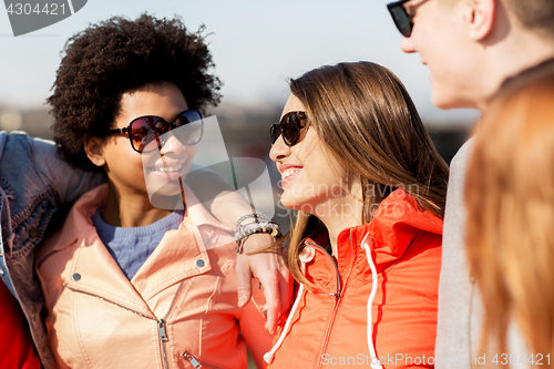 Image of happy teenage friends in shades talking on street