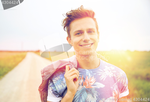 Image of smiling young hippie man on country road