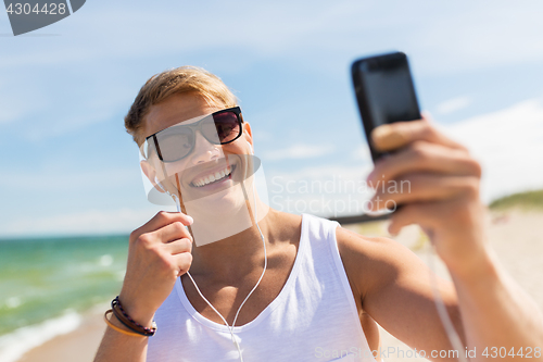 Image of man with smartphone taking selfie on summer beach