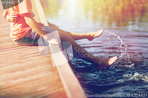 Image of happy teenage couple sitting on river berth