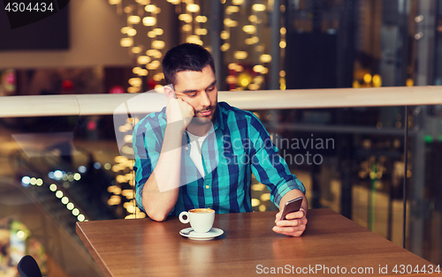 Image of man with smartphone and coffee at restaurant