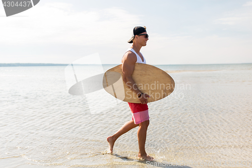 Image of happy young man with skimboard on summer beach