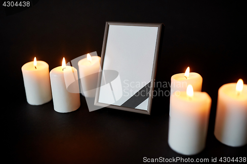 Image of black ribbon on photo frame and candles at funeral