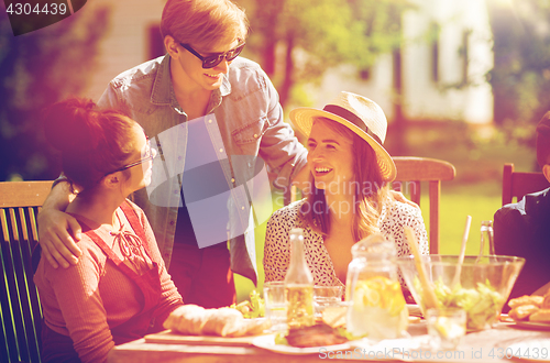 Image of happy friends having dinner at summer garden party