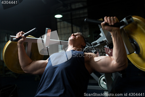 Image of man doing chest press on exercise machine in gym