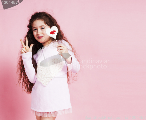 Image of little cute girl with candy on pink background posing emotional, lifestyle people concept 