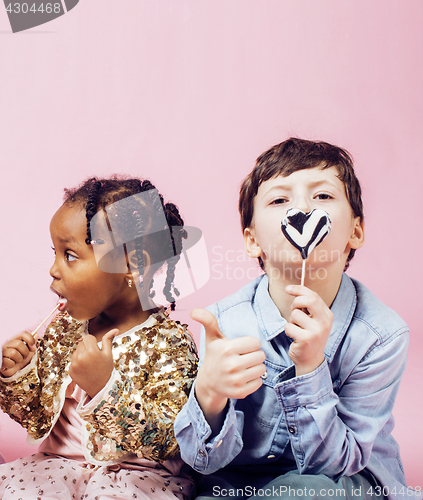 Image of lifestyle people concept: diverse nation children playing together, caucasian boy with african little girl holding candy happy smiling