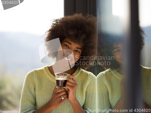 Image of African American woman drinking coffee looking out the window