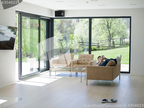 Image of young man using a mobile phone  at home