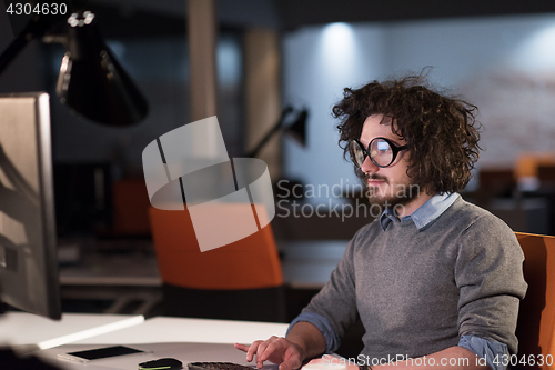 Image of man working on computer in dark startup office