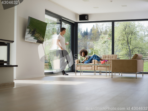 Image of multiethnic couple relaxing at  home with tablet computers