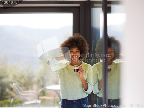 Image of African American woman drinking coffee looking out the window