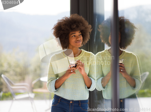 Image of African American woman drinking coffee looking out the window