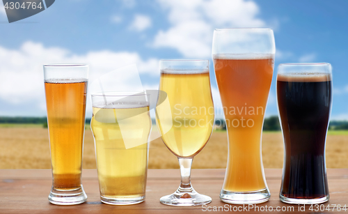 Image of different types of beer glasses over cereal field