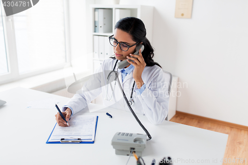 Image of doctor with clipboard calling on phone at hospital