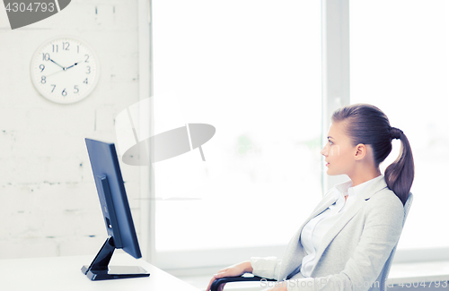 Image of businesswoman looking at wall clock in office