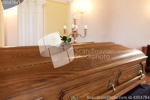 Image of rose flower on wooden coffin at funeral in church