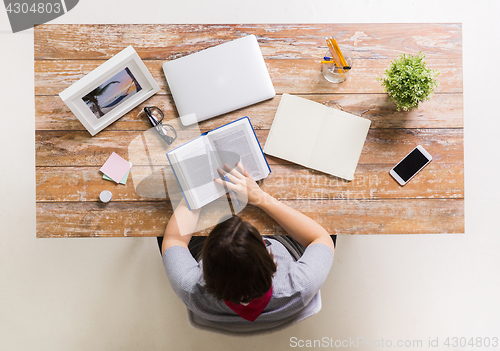 Image of woman reading book at wooden table