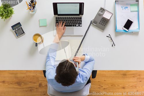 Image of businesswoman calling on phone at office table