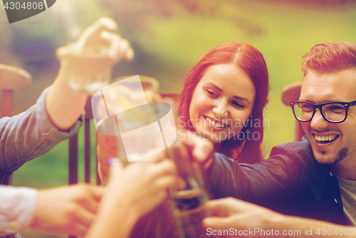 Image of happy friends clinking glasses at summer garden