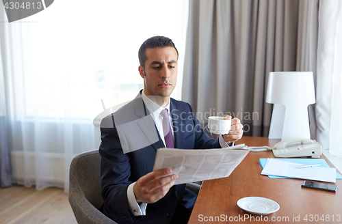 Image of businessman reading newspaper and drinking coffee