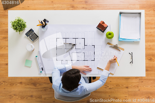 Image of architect with blueprint writing to clipboard