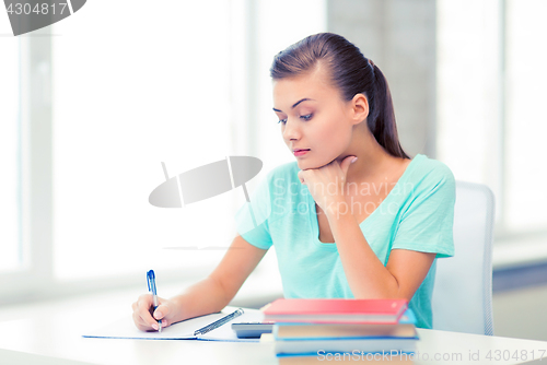 Image of tired student writing in notebook