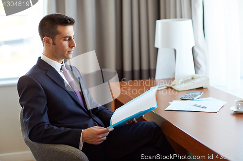 Image of businessman with papers working at hotel room