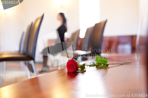 Image of red roses and woman crying at funeral in church