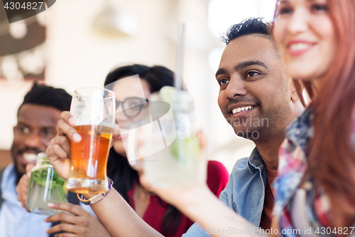 Image of happy friends with drinks at restaurant