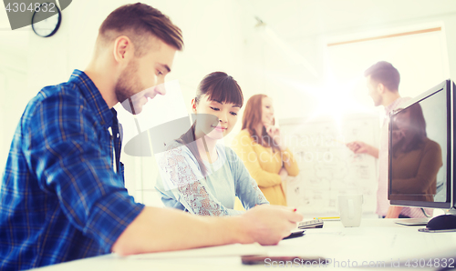 Image of creative team with blueprint at office