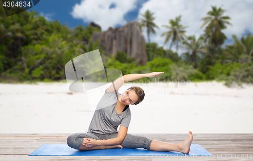 Image of happy woman doing yoga and stretching on beach