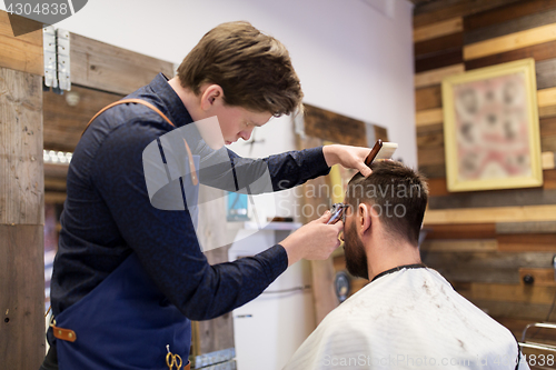 Image of man and barber with trimmer cutting hair at salon