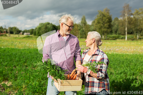 Image of senior couple with box of carrots on farm