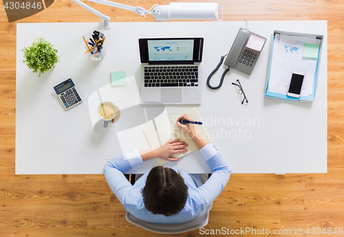 Image of businesswoman writing to notebook at office