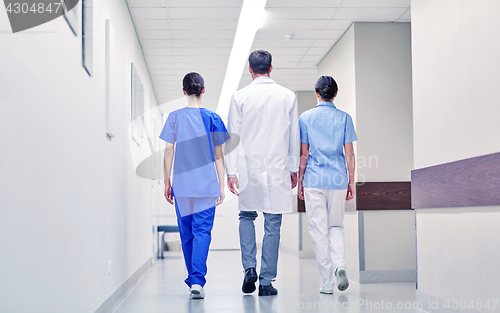 Image of group of medics or doctors walking along hospital