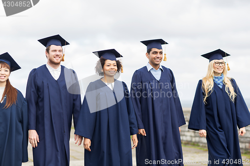 Image of happy students or bachelors in mortar boards