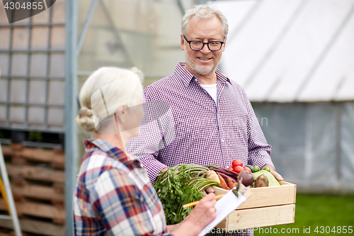 Image of senior couple with box of vegetables on farm