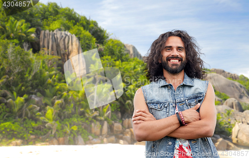 Image of smiling hippie man in denim vest on island beach