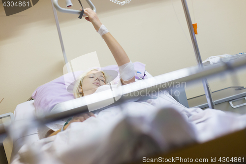 Image of Bedridden female patient recovering after surgery in hospital care.