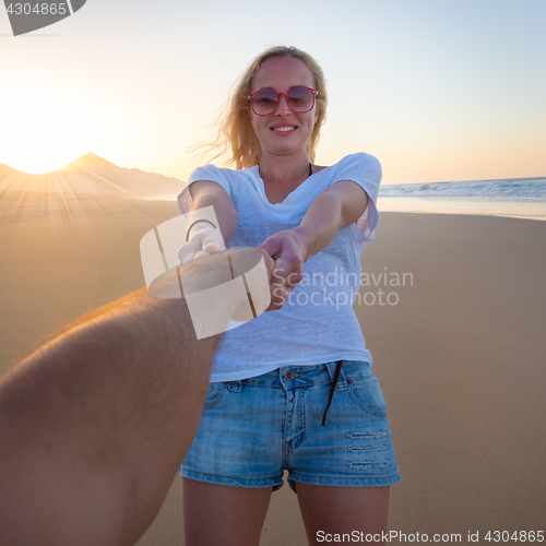 Image of Romantic couple, holding hands,  on beach.