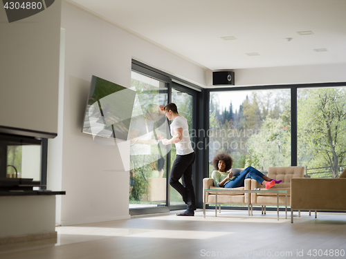 Image of multiethnic couple relaxing at  home with tablet computers