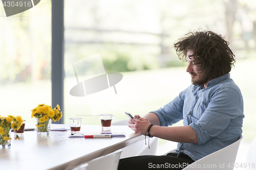 Image of young man using a mobile phone  at home