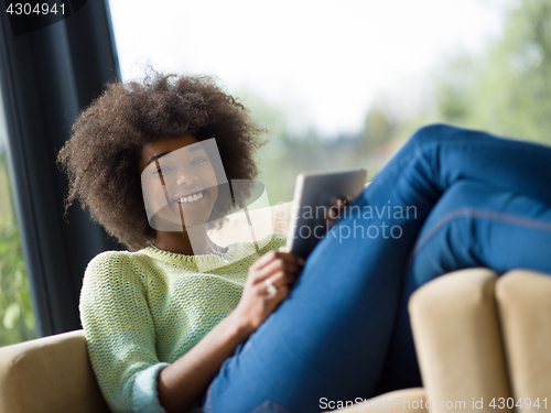 Image of young african american woman at home using digital tablet