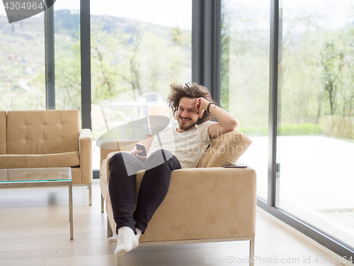 Image of young man using a mobile phone  at home