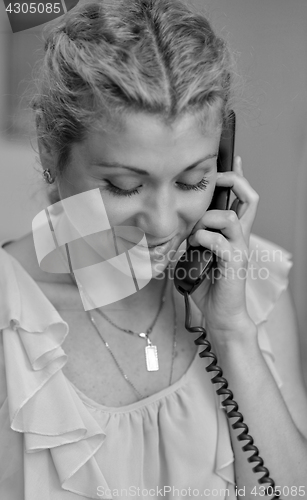 Image of Smiling girl talking on wire telephone