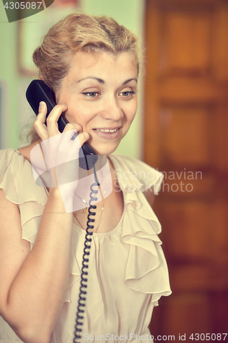 Image of Smiling girl talking on wire telephone