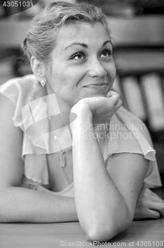 Image of Dreamy smiling girl sitting at the table