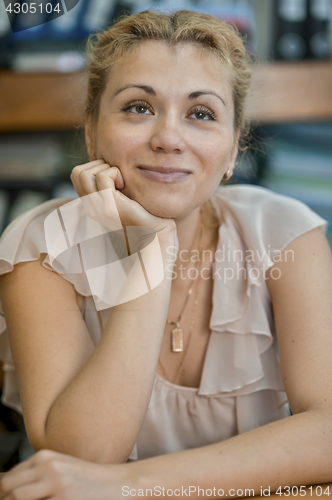 Image of Dreamy smiling girl sitting at the table